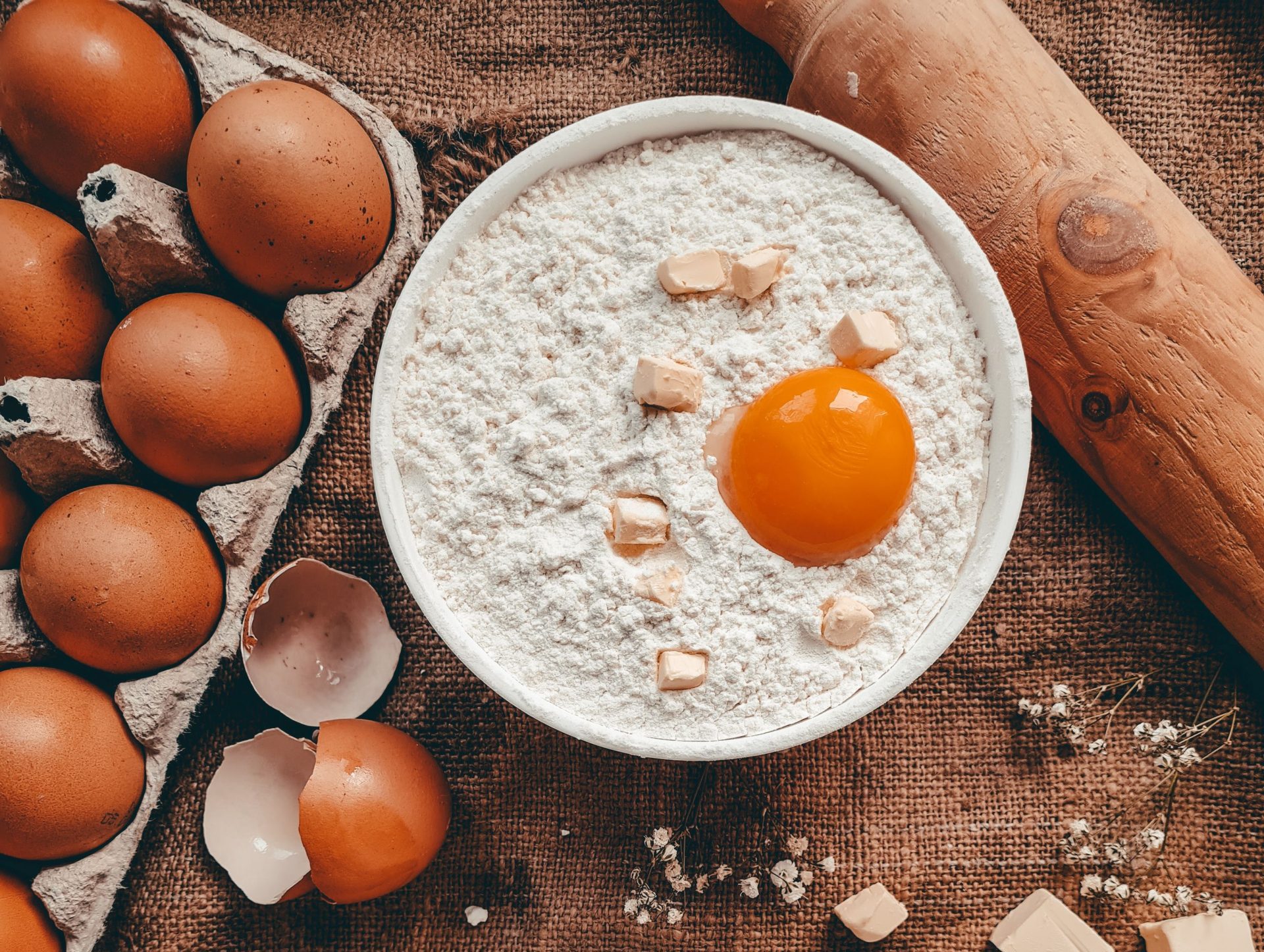 A cozy flat lay of baking ingredients, featuring eggs, flour, butter, and cottage cheese on a rustic surface.